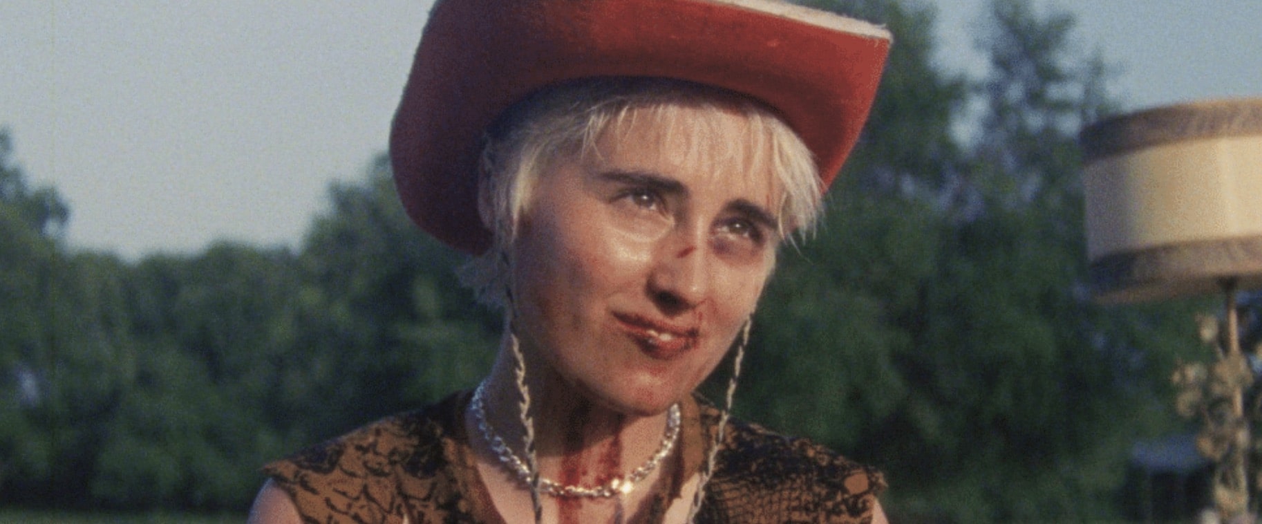 Still from "F*cktoys"; a bloodied person smirks while wearing a cowboy hat.